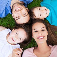 Mother father and two children laying on ground smiling at camera