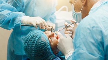 a dentist surgically placing dental implants into a patient’s mouth
