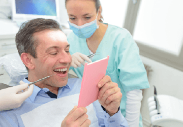 Man in dental chair looking at smile in mirror