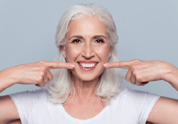 Older woman pointing to her smile