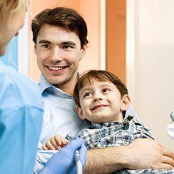 Man holding child in lap in dental chair