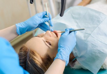 Dentist with blue gloves examining patient's teeth