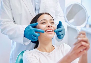 Young woman smiling at reflection in handheld mirror