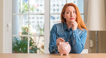 Woman putting coin into a piggy bank