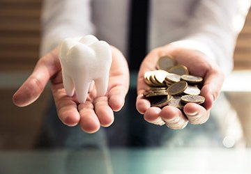 a person holding out two hands, one with coins, and the other with a tooth