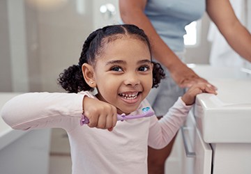 a child smiling as they’re about to brush their teeth