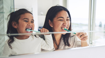 Mother and daughter brushing their teeth together
