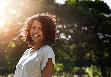 person smiling and taking a walk in a park