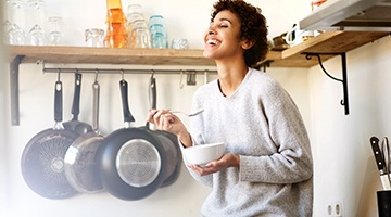 person enjoying a bowl of cereal while sitting on their kitchen counter