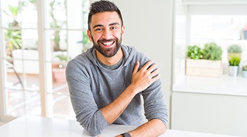 a person smiling and leaning on their kitchen counter