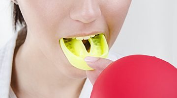 person putting a yellow mouthguard over their teeth 