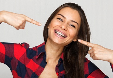 Woman smiling and pointing to her braces