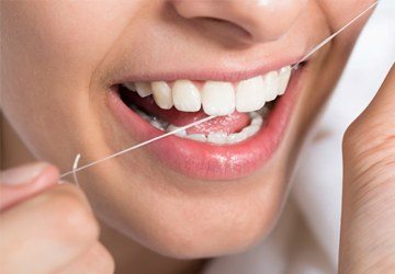 A woman flossing her teeth