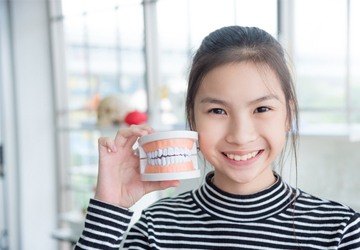 happy child holding model of teeth