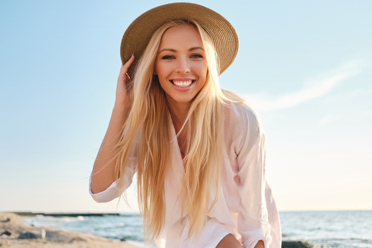 Woman wearing a sun hat and smiling during summertime.