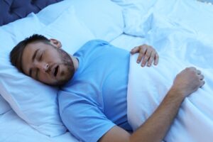 Man in blue shirt sleeping with mouth open